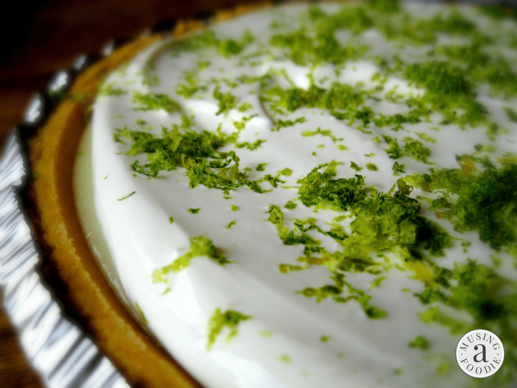Close up shot of fresh lime zest on top of a homemade key lime pie.
