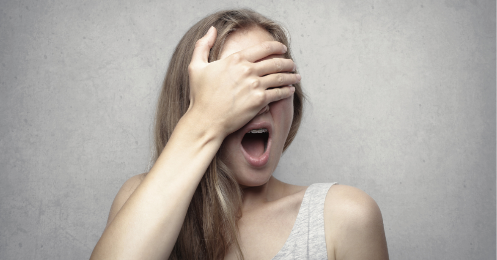 Woman with her hand held up to her face covering her eyes with an expression of shock.