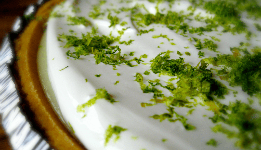 Homemade Key Lime Pie Recipe Close up shot of homemade key lime pie with a sour cream topping and fresh lime zest.
