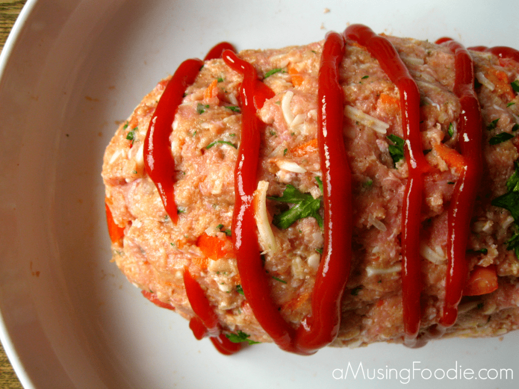Turkey Meatloaf Close up shot of uncooked turkey meatloaf with a line of ketchup swirled on top.