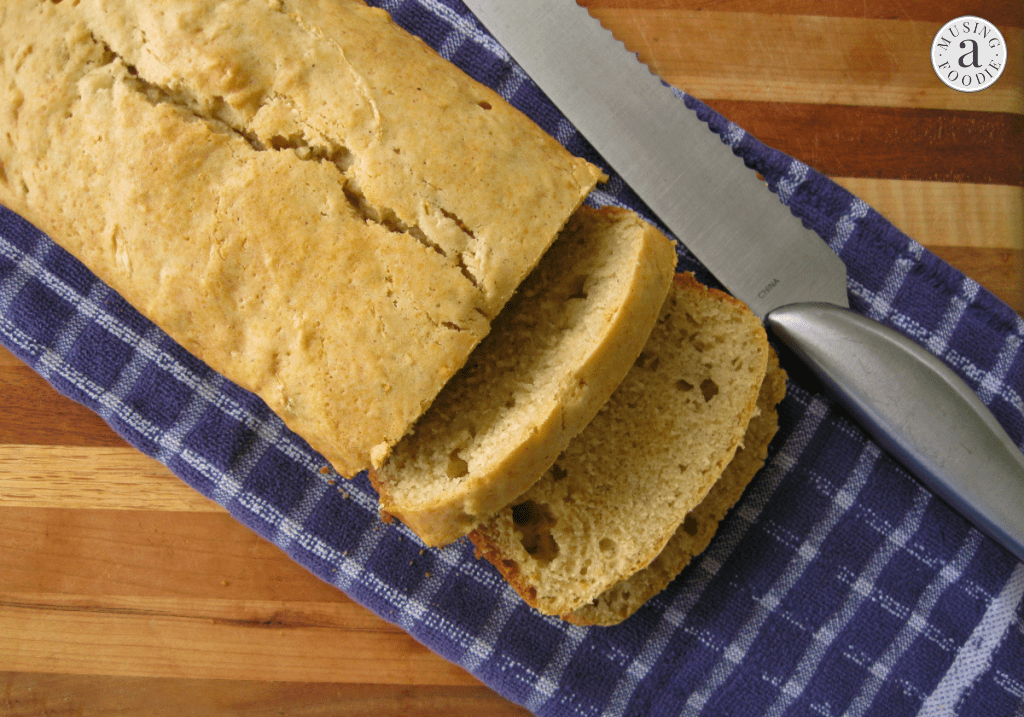 Honey lemon zucchini bread loaf on a blue and white towel, with two slices cut.