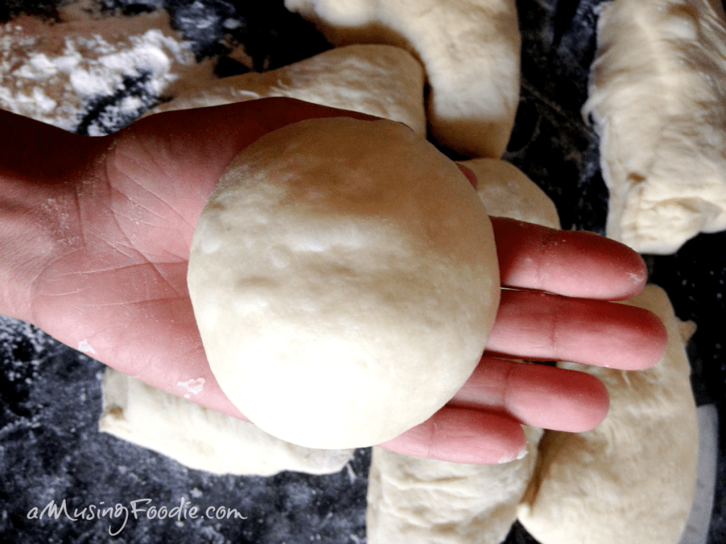 Small round of dough with a smooth top sitting in a hand.