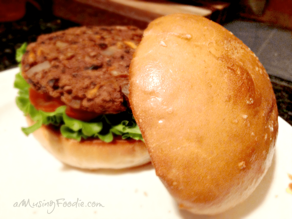 Close up of a veggie burger with lettuce and tomato on a homemade hamburger bun.