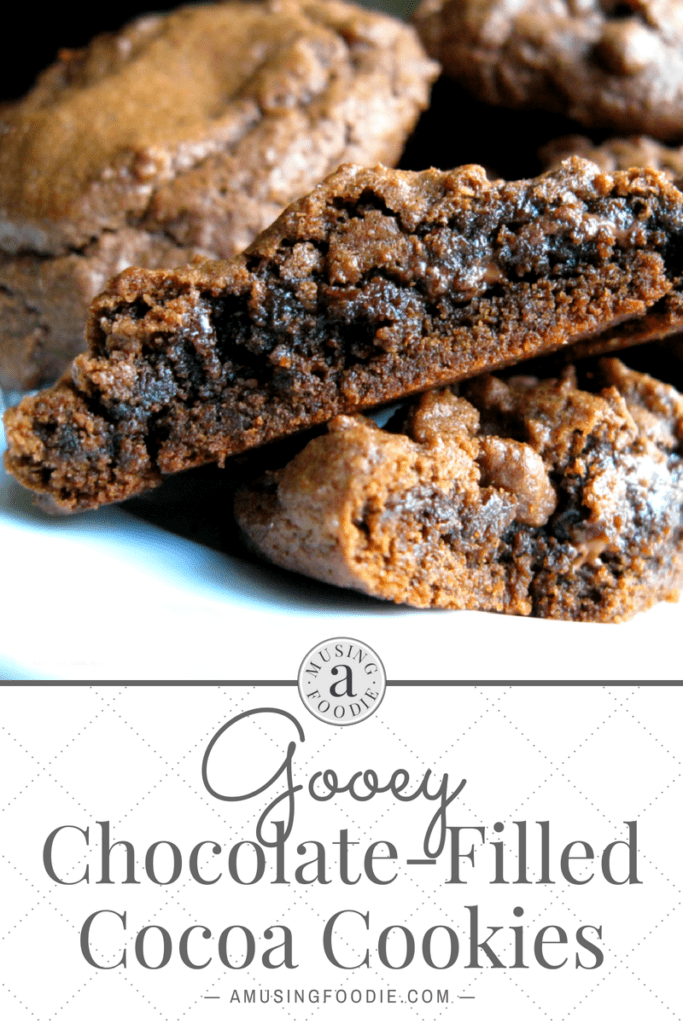 Close up of a chocolate cookie cut in half, the center looks gooey. More of the same cookie are in the background. Text below the image is on a white background: Gooey Chocolate-Filled Cocoa Cookies, amusingfoodie.com