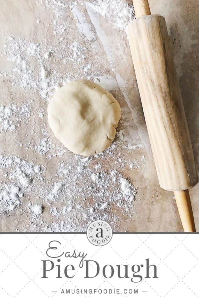Disk of pie dough on a floured counter with a rolling pin.
